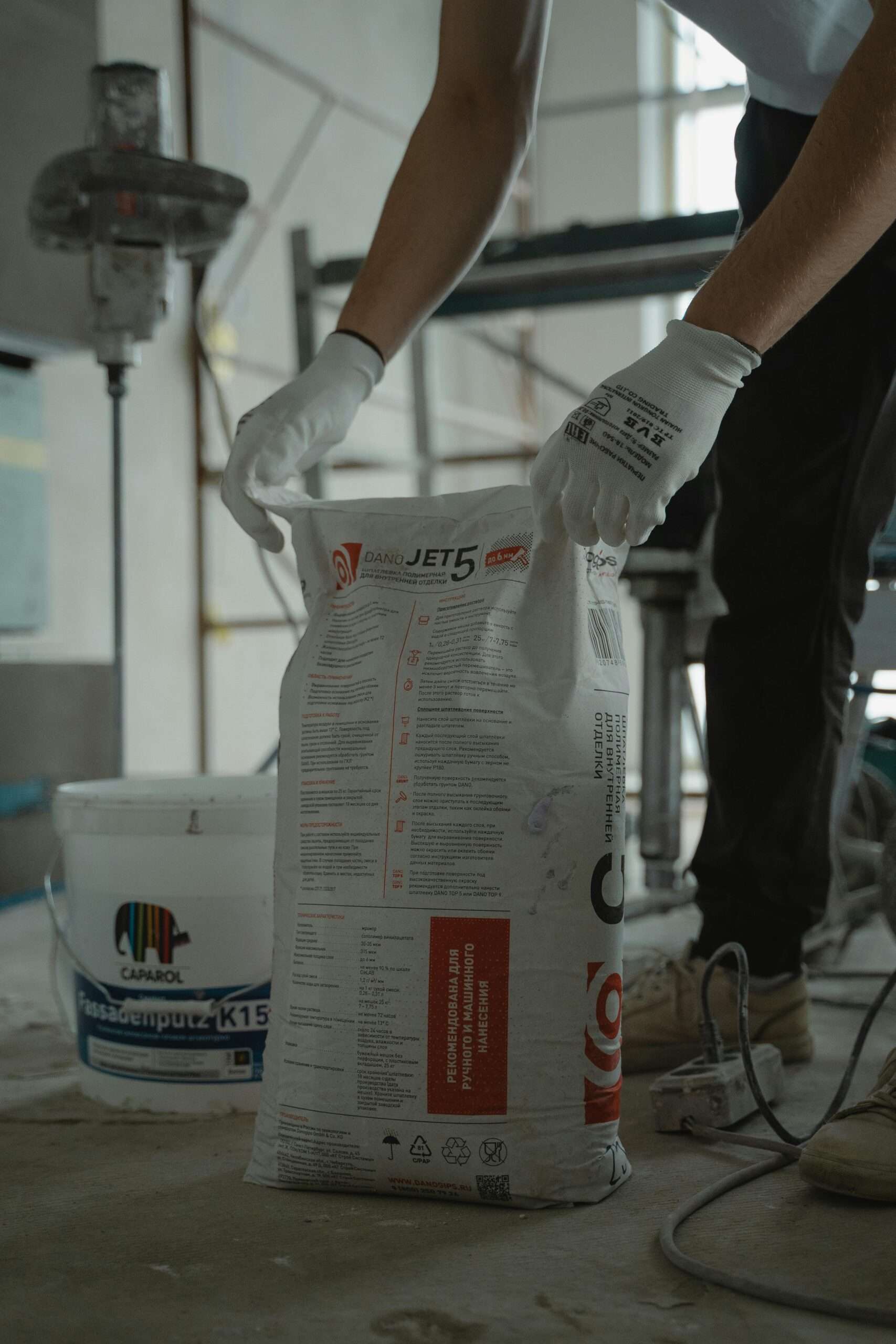 Worker handling cement bag in an indoor renovation project, wearing gloves for safety.